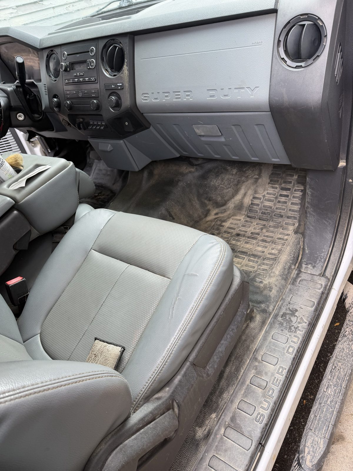 Before: dust and grime caked on the passenger floor mat and seat of a work truck